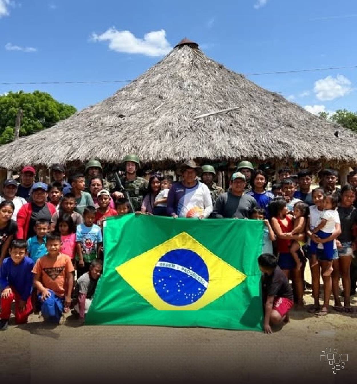 Militares do Exército e moradores de comunidade indígena reunidos diante de uma construção tradicional em Roraima